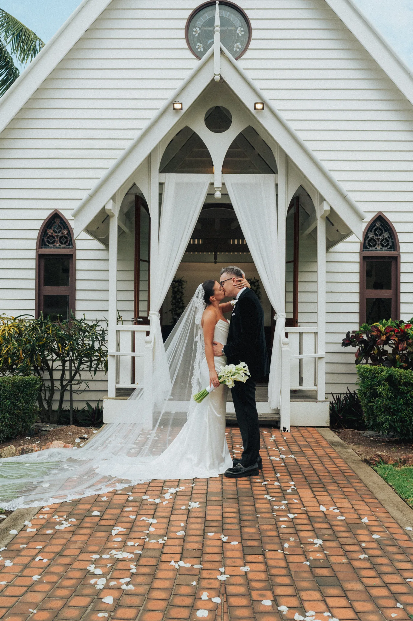 The bride walks toward a white island chapel framed by palm trees