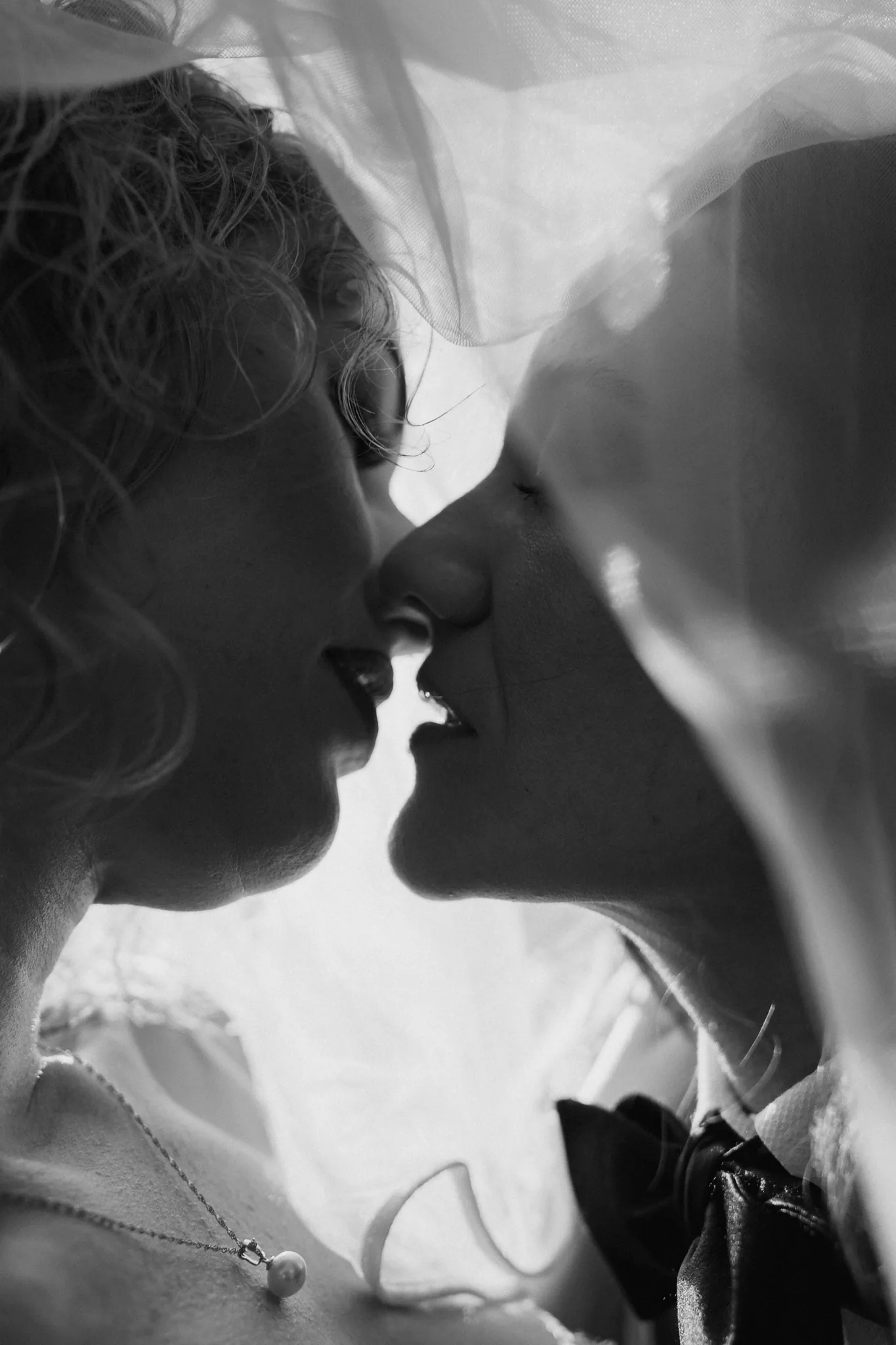 A close, tender kiss with hands cradling each other's faces, in black and white