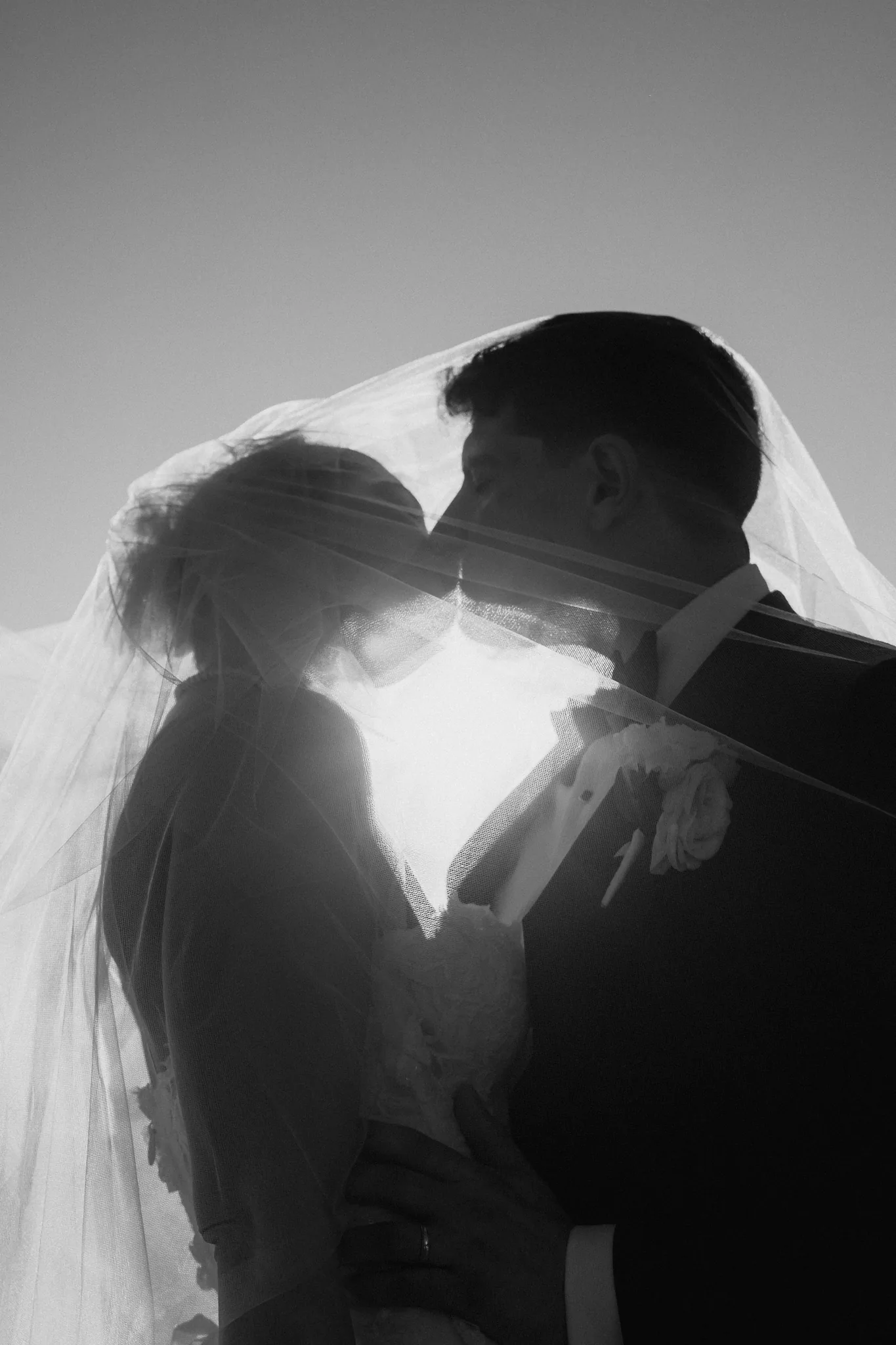 A silhouetted kiss with the sun flaring between them, in black and white